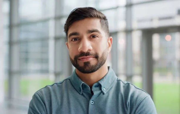 gettyimages-2148808570-612×612 Portrait, closeup and man with confidence in office, workspace and conference room with happiness for corporate career. Male person, intern and employee for banking firm, investment or trade company