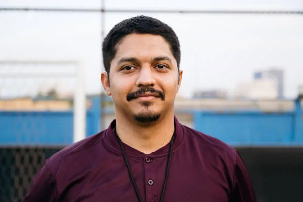 gettyimages-2156461633-612×612 Portrait of confident male soccer coach wearing jersey. Instructor is standing at training ground. He is having facial hair.